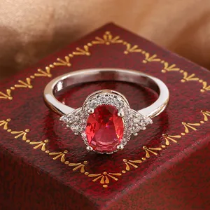 Detail shot of elegant oval faux ruby ring with micro-pave diamonds on red box