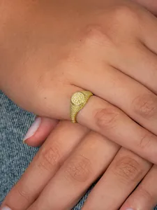 Close-up of a gold-plated oval hip hop ring with pave-set 5A cubic zirconia