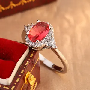 Close-up view of elegant oval red gemstone ring with a sparkling crystal halo setting