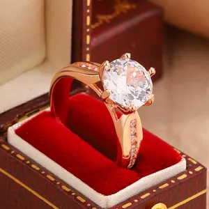 Detailed close-up view of a rose gold six-prong moissanite ring in a red velvet gift box.