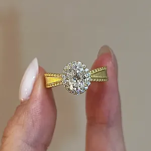 Macro view of a luxurious golden oval halo ring featuring a sparkling simulated gemstone