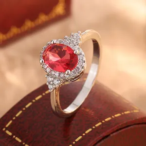 Close-up of luxury oval red faux ruby ring with white zircon pave set in gold band