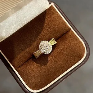 Close-up of elegant gold-tone oval halo ring with textured band in jewelry box