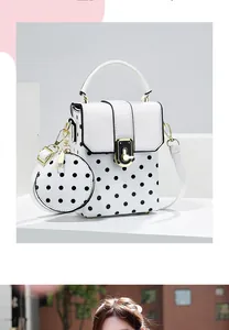 Detail of a white polka dot crossbody bag with an attached matching round coin purse.