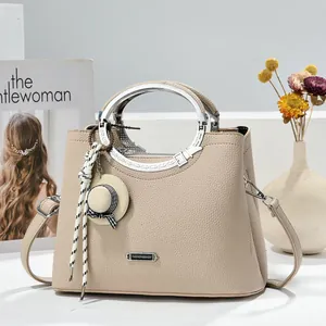 Detail view of beige litchi grain handbag with silver metal handle and hat pendant