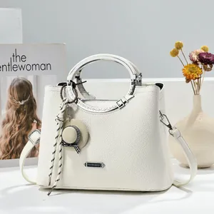 Detail of white lychee pattern leather handbag with metal handles and a mini hat charm