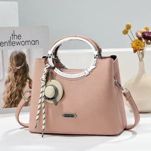 Casual pink lychee texture leather handbag with silver circular handle and decorative charm
