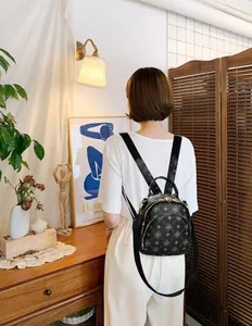 Vista posteriore di una donna con un mini zaino nero a fiori in una stanza accogliente