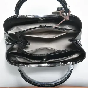 Interior detail view of black lychee grain handbag showing multiple compartments and lining