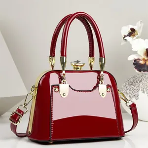 Elegant glossy red handbag with gold hardware and adjustable shoulder strap detail