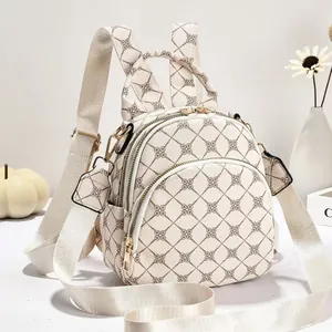 Vista dettagliata di un elegante mini zaino crema con monogramma e spallacci regolabili