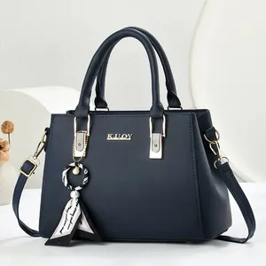 Elegante marineblauwe handtas met goudkleurig logo en een stijlvolle sjaalhanger.