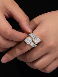Close-up of a geometric gold-plated open ring with sparkling white zircons on a hand