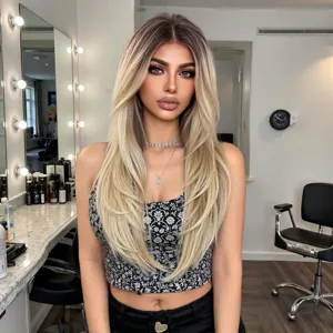 Close-up of long blonde layered straight wig with gradient roots in salon setting