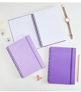 Vista superior de cuadernos de espiral A5 púrpuras con páginas de puntos y goma