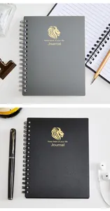 Nahaufnahme von zwei A6 Spiralnotizbüchern mit goldgeprägtem Löwenlogo und Journal-Text