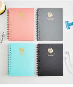 Vier A6-Spiralnotizbücher in verschiedenen Farben mit goldenen Löwenlogos und Journal-Slogan.