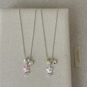Detail view of two silver necklaces featuring pink and white enamel flower pendants.