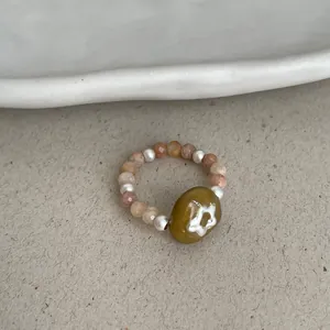 Close-up view of an elastic ring featuring natural stones, pearls, and flower bead
