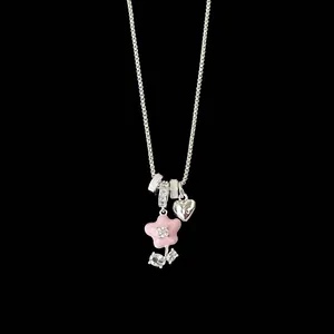 Detailed view of silver necklace with pink enamel flower charm and heart pendant