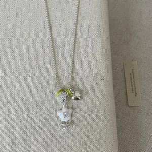Close-up detail of silver-tone necklace with white flower and heart pendants