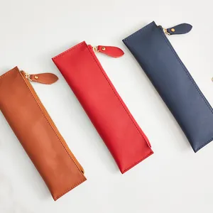 Tre astucci minimalisti in vera pelle nei colori marrone, rosso e blu navy con zip
