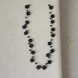 Detailweergave van handgemaakte zwarte kralenketting met bloemen op een canvas achtergrond