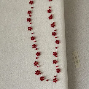 Detailweergave van handgemaakte ketting met rode kristallen kralen in bloempatronen