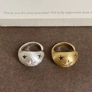 Primo piano di anelli spazzolati oro e argento con stelle traforate e zirconi.
