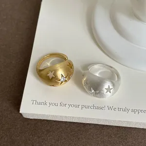 Dettaglio di anelli spazzolati con stelle intagliate e pietre di zircone micro.