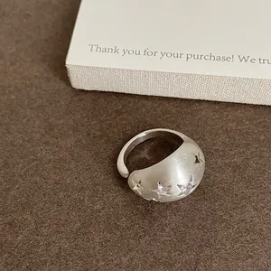 Dettaglio di un anello ovale in argento spazzolato con stelle intagliate e zirconi