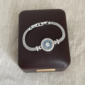 Vue détaillée d'un bracelet argenté doté d'un compas rotatif orné de zircons bleus.