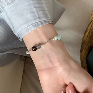 Elegante pulsera de plata minimalista con piedras naturales de colores en la muñeca.