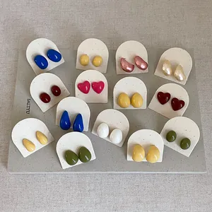 Close-up of colorful dopamine style enamel heart and bean stud earrings on cards