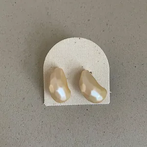 Detailed view of faceted champagne bean-shaped stud earrings on a textured display card