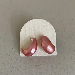 Macro view of pink metallic bean earrings with irregular hammered texture on arch card