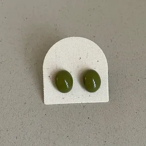 Macro detail of minimalist olive green oval stud earrings with a glossy bean-shaped finish