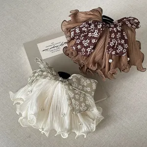 Detail showing pleated fabric hair claw with floral bow and pearl accents