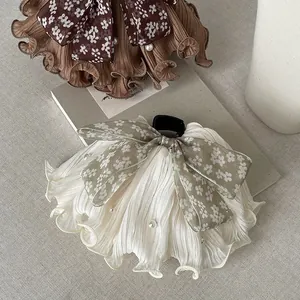 Detailed macro view of elegant floral bow hair claw with pearl accents and pleated ruffles