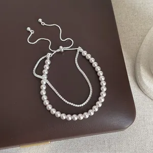 Elegant double-layer pearl and rhinestone bracelet displayed on a brown leather box