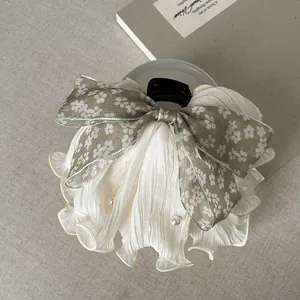 Detailed view of an olive green floral bow hair claw clip with elegant pearl ruffles