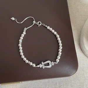 Close-up of elegant pearl bracelet with crystal-encrusted horseshoe clasp detail