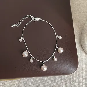 Detailed view of an elegant silver chain bracelet with pink pearls on brown leather