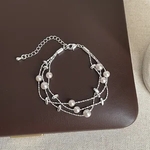 Close-up detail of an elegant multi-strand pearl bracelet with silver-tone beads