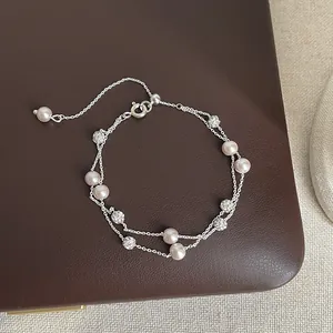 Macro view of a double-layered silver bracelet with pink pearls and crystal beads