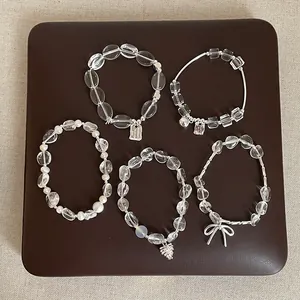 Vue détaillée de plusieurs bracelets en cristal de roche clair avec breloques argentées.
