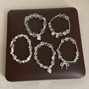 Gros plan de cinq bracelets minimalistes en cristal blanc irrégulier avec breloques