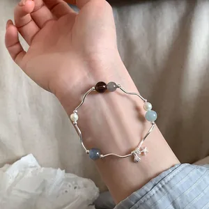 Vista detallada de una pulsera minimalista de estrella de mar y concha con piedras naturales