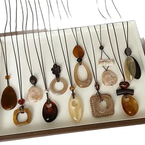 Collezione di collane lunghe con pendenti geometrici in resina in tonalità terra naturali