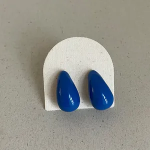 Macro detail of blue drip oil geometric bean stud earrings with a glossy finish.